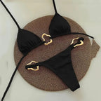 Sleek black halter triangle micro bikini set with gold accents on a woven background, perfect for summer swimwear.