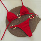 Sleek red halter triangle micro bikini set displayed on a textured round mat, perfect for swimwear trends 2024.